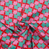 Coated poplin printed with polka dots & green clover on a red background