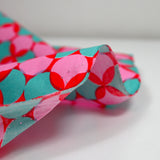 Coated poplin printed with polka dots & green clover on a red background