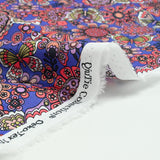 Coton imprimé papillon corail fond violet au mètre