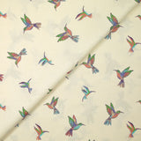 Algodón estampado con un vuelo de colibríes sobre fondo crudo