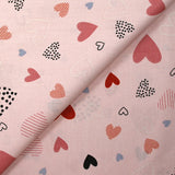 Cotton poplin printed with lots of hearts on a light pink background