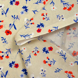 Cotton poplin printed with blue, white and red flowers on a greige background
