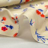 Cotton poplin printed with blue, white and red flowers on a greige background