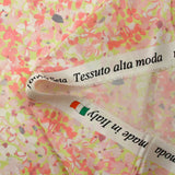 Silk satin printed with coral pink flowers on a pastel green background