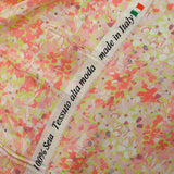 Silk satin printed with coral pink flowers on a pastel green background