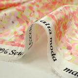 Silk satin printed with coral pink flowers on a pastel green background