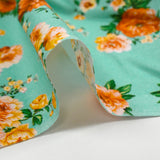 Cotton poplin printed with orange bouquet on a water green background