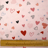Cotton poplin printed with lots of hearts on a light pink background