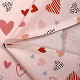 Cotton poplin printed with lots of hearts on a light pink background