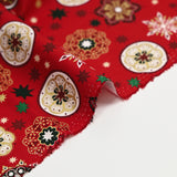 Popelina de algodón estampada con medallones navideños y copos de nieve sobre fondo rojo