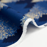 Popelina de algodón estampada con abetos brillantes sobre fondo azul medianoche