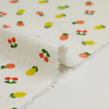 Punto pointelle de algodón con fondo tutti frutti blanquecino