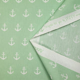 Algodón estampado con ancla marina blanca y fondo verde mar.